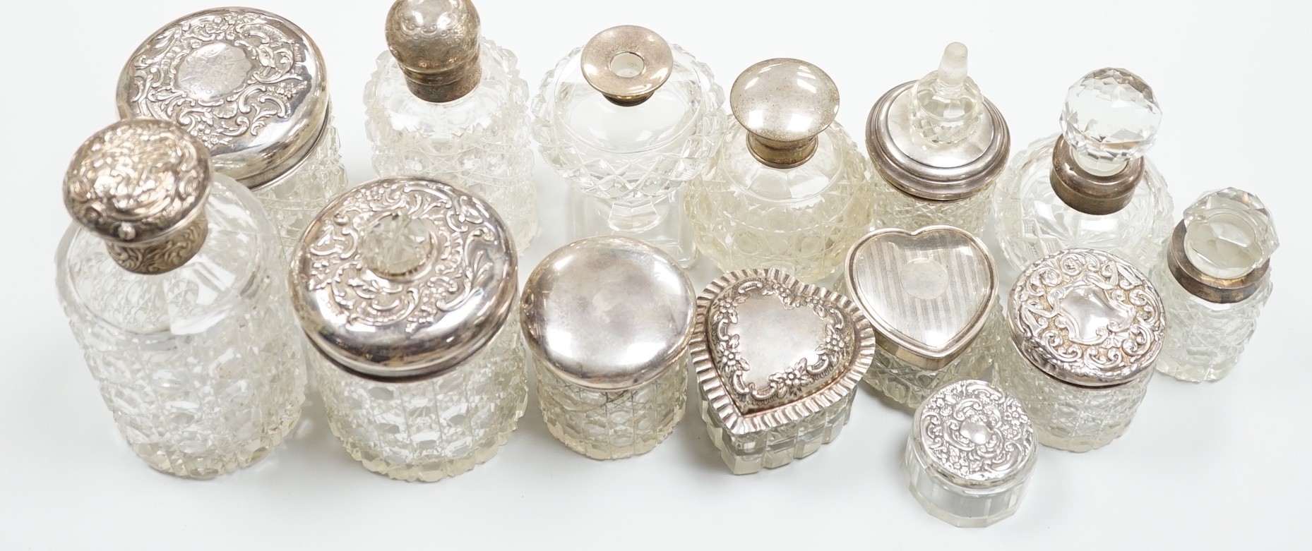 A collection of fourteen assorted late 19th/early 20th century silver mounted cut glass toilet jars or scent bottles, largest 15.5cm, some a.f.